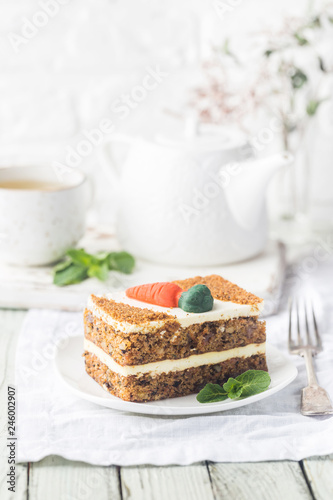 Slice of carrot cake with cream cheese frosting on wooden table