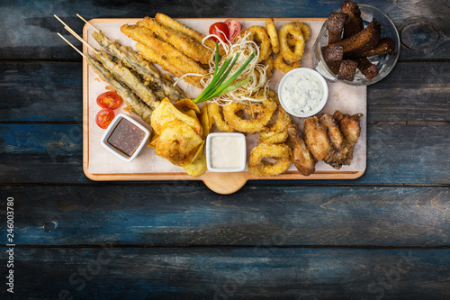 Beer snacks set. Fish set served on cutting board with the mugs, on the wooden background.