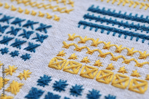 Different examples of blue and yellow square patterns of embroidery on white fabric