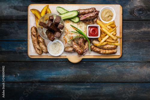 Beer snacks set. Grilled sausages and french fries with tomato and BBQ sauce, served on cutting board.