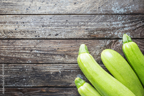 Fresh organic summer vegetables zucchini on rustic wooden background. Top view, space for text.