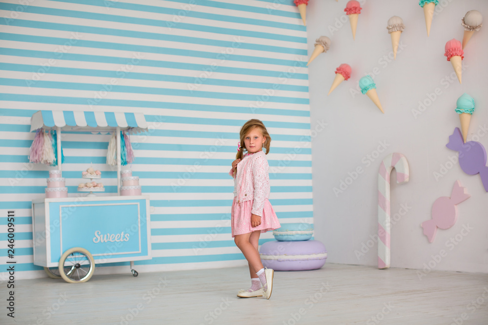 Naklejka premium Happy young girl on background of large candy and ice cream on wall