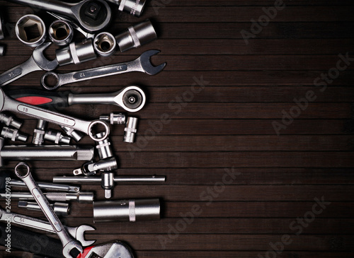a pile of adjustable and wrench spanners on a black wooden background