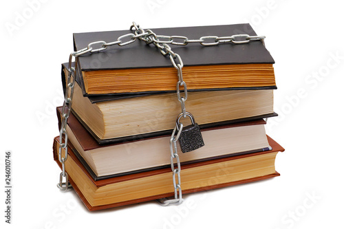 stack of various books wrapped by chain with padlock isolated on white background photo