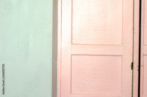 old wooden doors light pink color, painted with oil pink paint in a concrete wall painted in mint, light green color