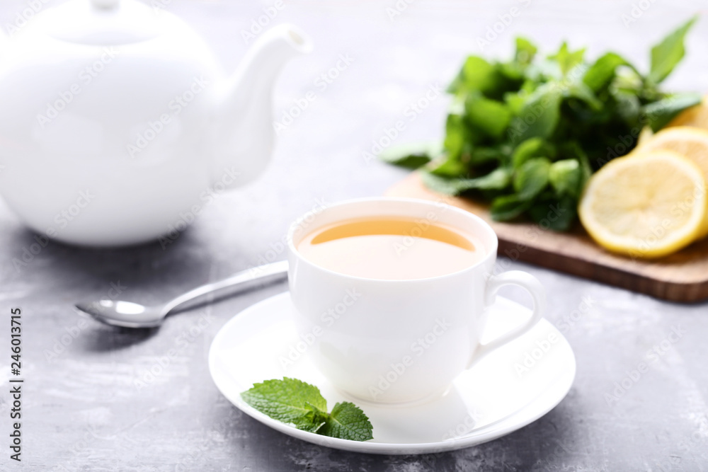 Cup of tea with mint leafs and teapot on wooden table Cup of tea with mint leafs and teapot on wooden table