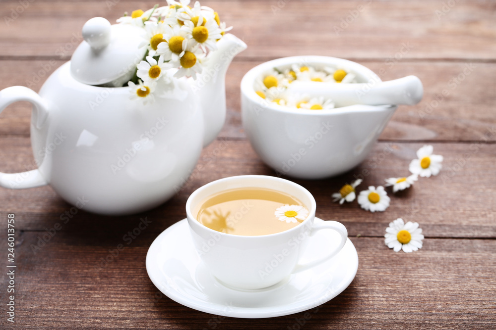Cup of tea with chamomile flowers on brown wooden table Cup of tea with chamomile flowers on brown wooden table