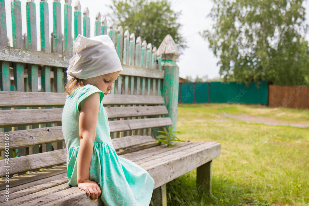 Obraz premium little girl sitting on a bench in the park