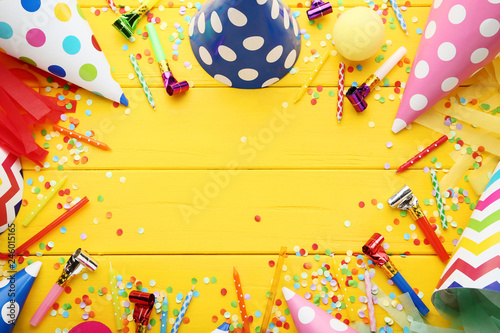 Birthday paper caps with blowers and candles on yellow wooden table