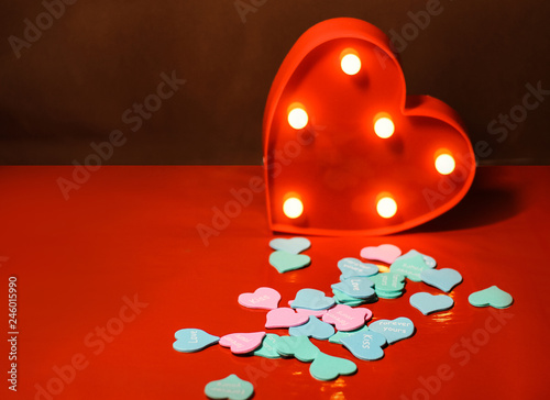 Glowing red heart with flashlights on the red background closeup 