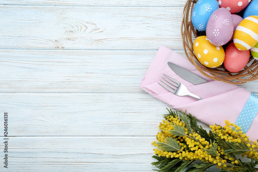 Kitchen cutlery with easter eggs and mimosa flowers on wooden table