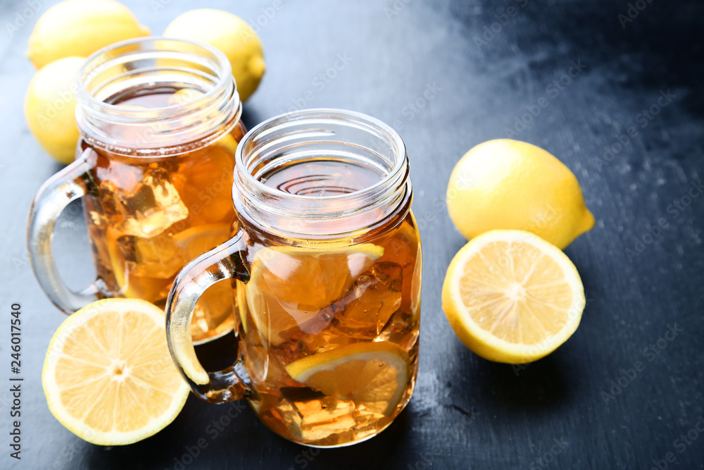 Ice tea in glass jars with lemon on wooden table Ice tea in glass jars with lemon on wooden table