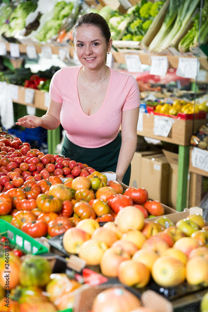 Salesgirl proposing fruits and vegetables in supermarket