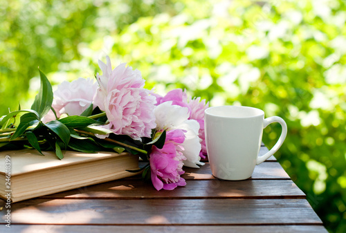  book, flowers and a cup of tea on a table in a spring garden, spring or summer card or calendar