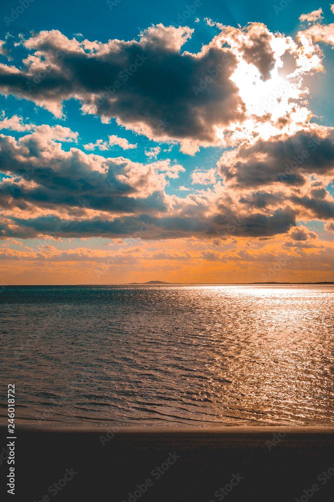 Naklejka premium darken beach in the afternoon sun with big clouds in the sky
