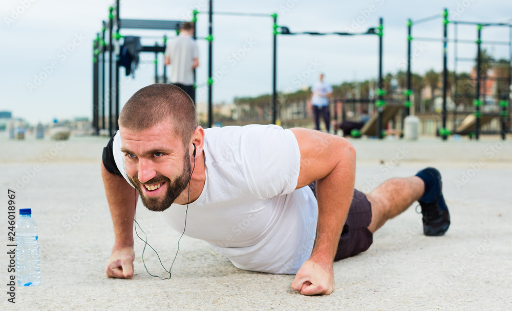 Fototapeta premium man performs push-ups on sportsground