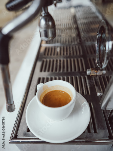 close-up view of glass cup with cappuccino and coffee machine