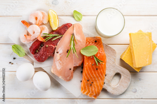 Selection of aminal protein sources - beef, chicken, salmon, cheese, milk, eggs, shrimps on wood background photo