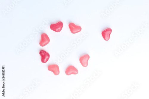Concept of a lonely heart made of heart shaped pink jelly sweets on isolated white background. Top view. Copy space.