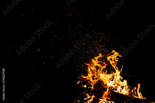 Burning woods with firesparks, flame and smoke. Strange weird odd elemental fiery figures on black background. Coal and ash. Abstract shapes at night. Bonfire outdoor on nature. Strenght of element. © benevolente