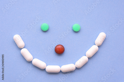 Several different pills types and colors like a smiley on blue background