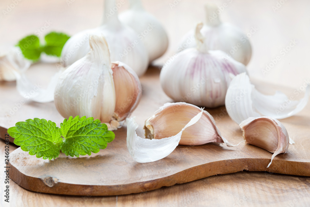 Garlics and fresh mint leaves on wooden board Garlics and fresh mint leaves on wooden board