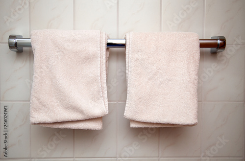 Zwei frische und gefaltete Badetücher hangen auf einer Stange im Badezimmer photo