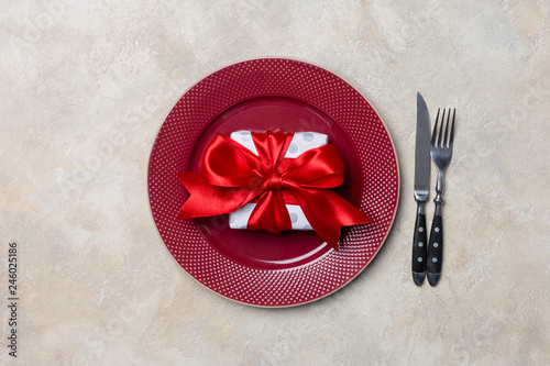 Red plate with gift box, with fork and knife at white background