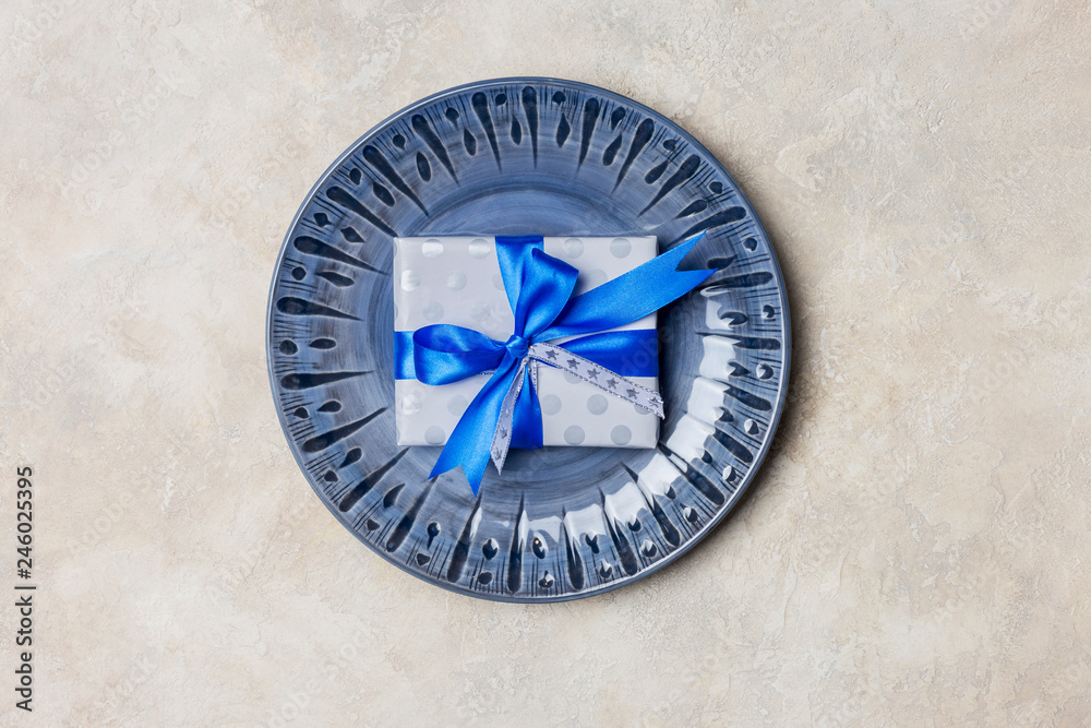 Blue plate with gift box with blue bow at white background