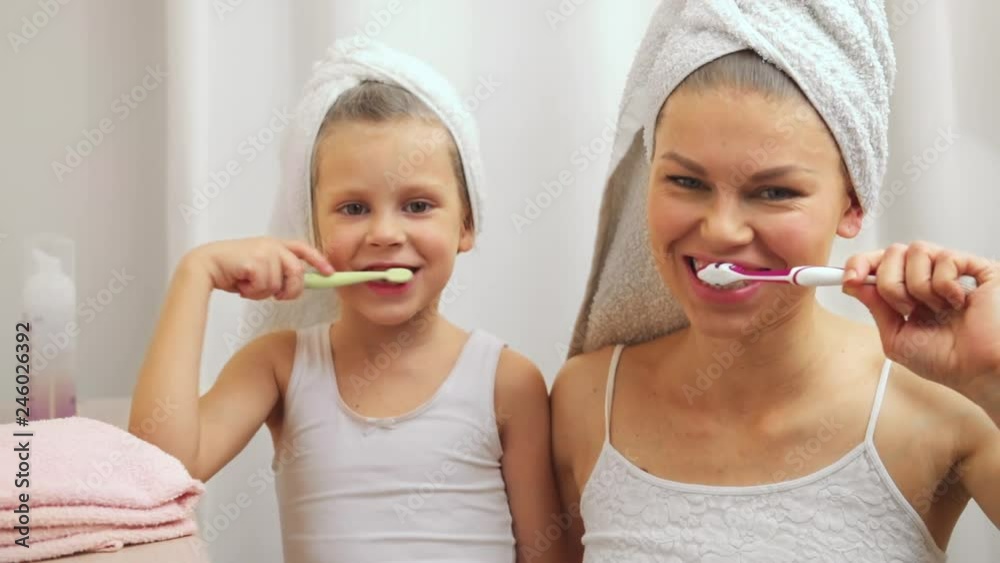Joyful child with her mother brushing teeth after bath. Concept of dental care and hygiene. Joyful child with her mother brushing teeth after bath. Concept of dental care and hygiene.