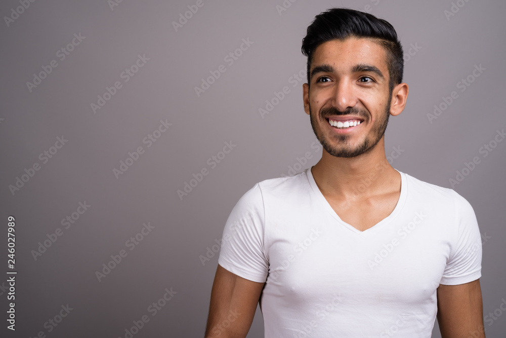 Obraz premium Young handsome Persian man against gray background