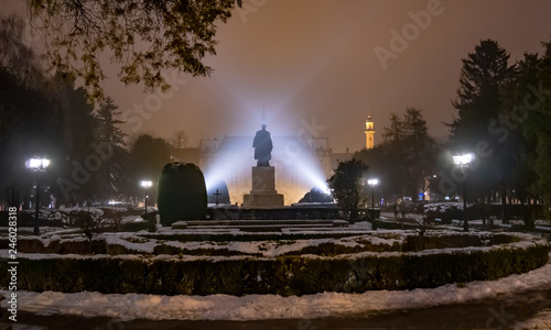 Evening scene outdoor in the main garden of Satu Mare with mysterious lights over Vasile Lucaciu statue, in winter season photo