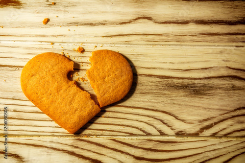 Broken Heart shaped ginger Cookies And Crumbs over wooden background, love concept
