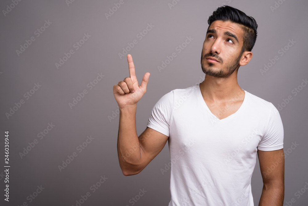 Young handsome Persian man against gray background Young handsome Persian man against gray background