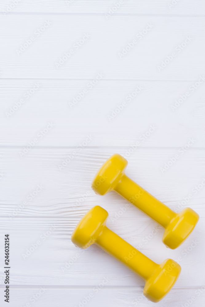 Small yellow dumbbells with copy space. Equipment for sport exercise. Fitness background. Small yellow dumbbells with copy space. Equipment for sport exercise. Fitness background.