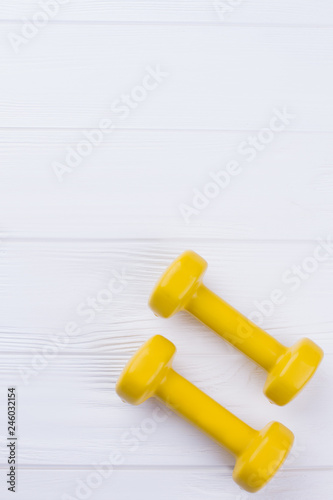 Small yellow dumbbells with copy space. Equipment for sport exercise. Fitness background.