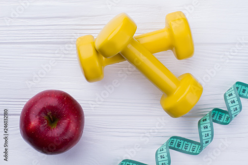 Dumbbells, red apple and measuring tape. Fitness and weight loss concept.
