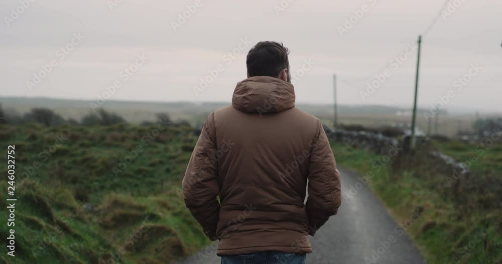 Countryside walking man in the evening in the middle of road , in the Ireland country , all green field around. Countryside walking man in the evening in the middle of road , in the Ireland country , all green field around.