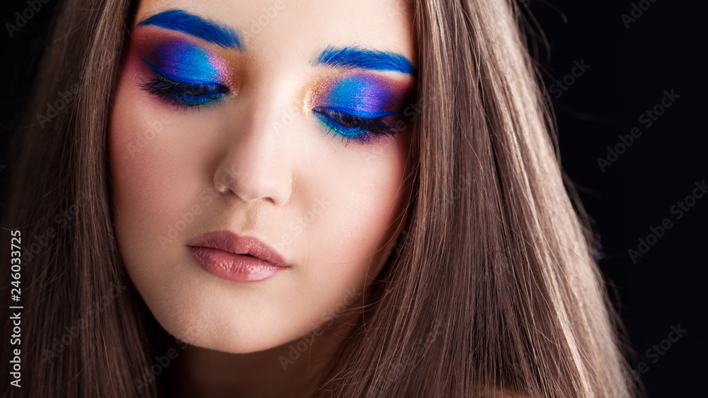 Naklejka premium Attractive brunette with bright stylish make-up. Colored Smokey eyes and blue eyebrows.