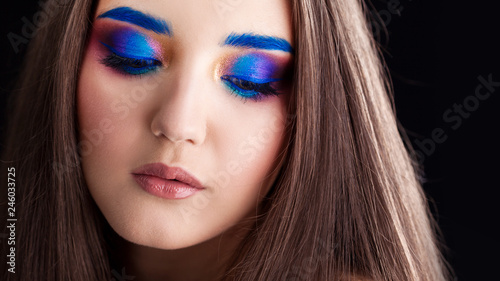 Attractive brunette with bright stylish make-up. Colored Smokey eyes and blue eyebrows.
