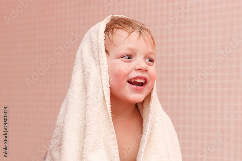 Adorable baby boy sitting under a hooded towel after bath.