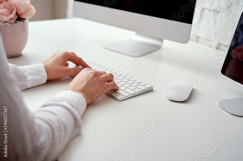 Fotografie Closeup of blurred female hands typing on white keyboard who is working at offic