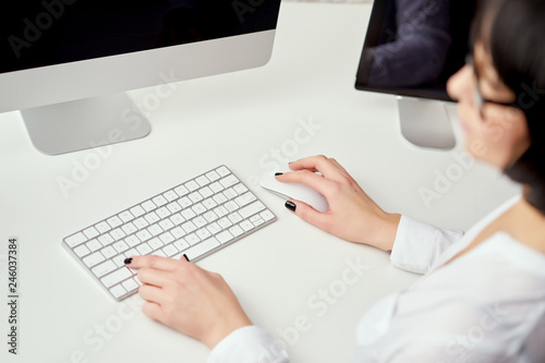 Closeup of blurred female hands typing on white keyboard who is working at office and using computer