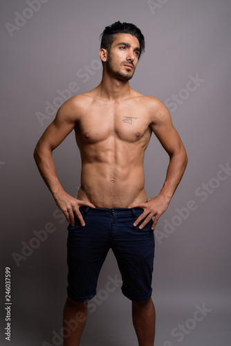 Young handsome Persian man shirtless against gray background