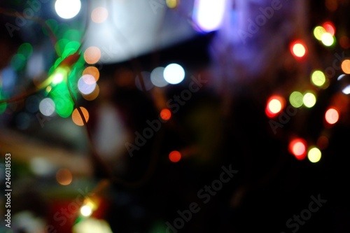 Blurred colorful light bulbs hanging on a wire and glowing in the dark night with plenty yellow bokeh background 