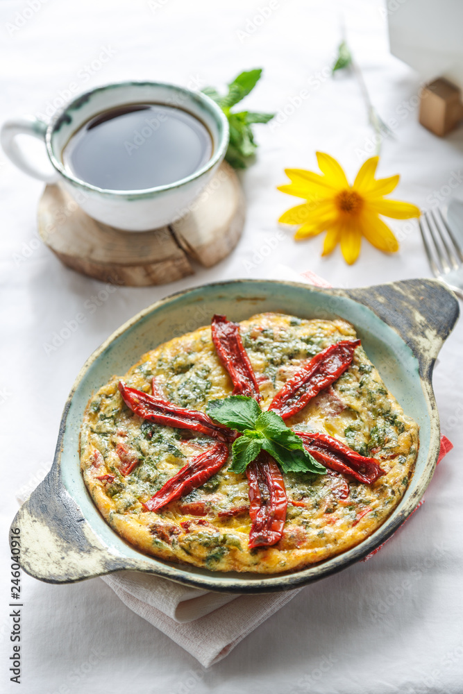 Traditional fritatta with dry tomatoes in a cast iron pan. White background, copy space Traditional fritatta with dry tomatoes in a cast iron pan. White background, copy space