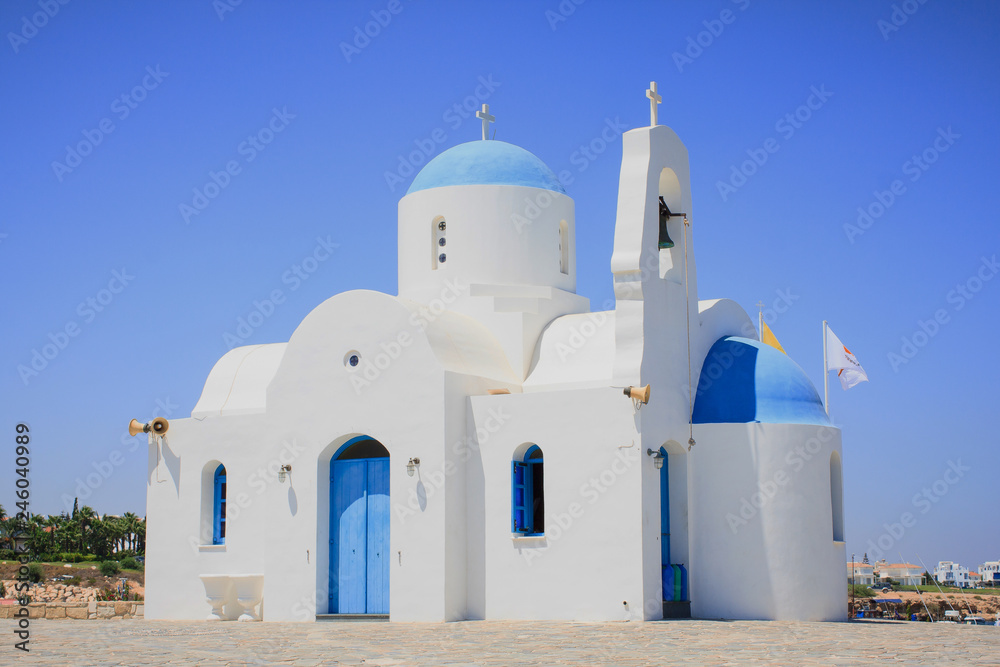 A large white church with a blue roof with a bell tower in the beach on the island of Cyprus