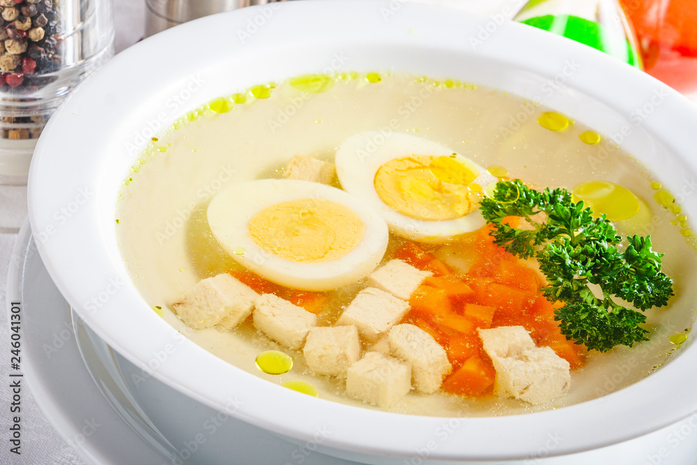 Chicken clear soup with carrot and egg in white plate. Close up Chicken clear soup with carrot and egg in white plate. Close up