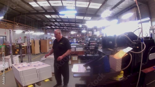 A printing machinist loading paper into his press, getting it ready to start printing.