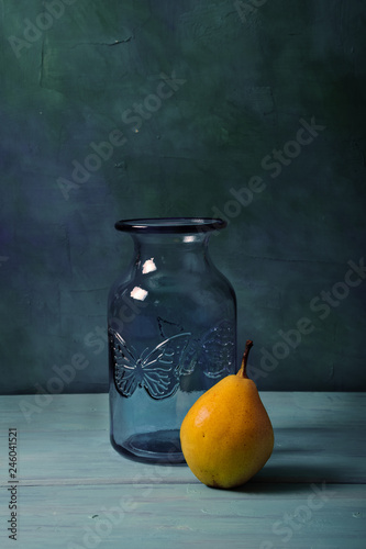 Obraz na plátně Still life with blue glass vase and fruits on turquoise background